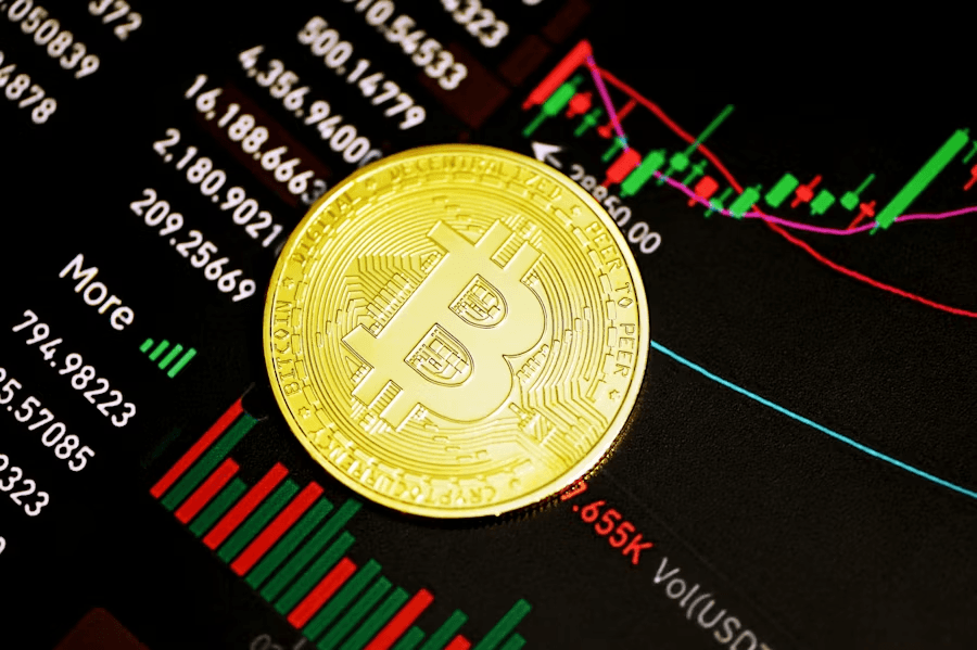 Golden Bitcoin coin lying on a screen with price charts and trading data in green and red